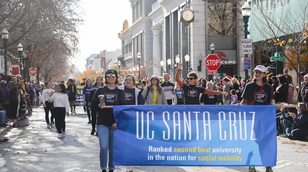 Photo of 2019 UCSC parade with First Gen Initiative students holding up a sign that reads "UCSC ranked second best university in the nation for social mobility"
