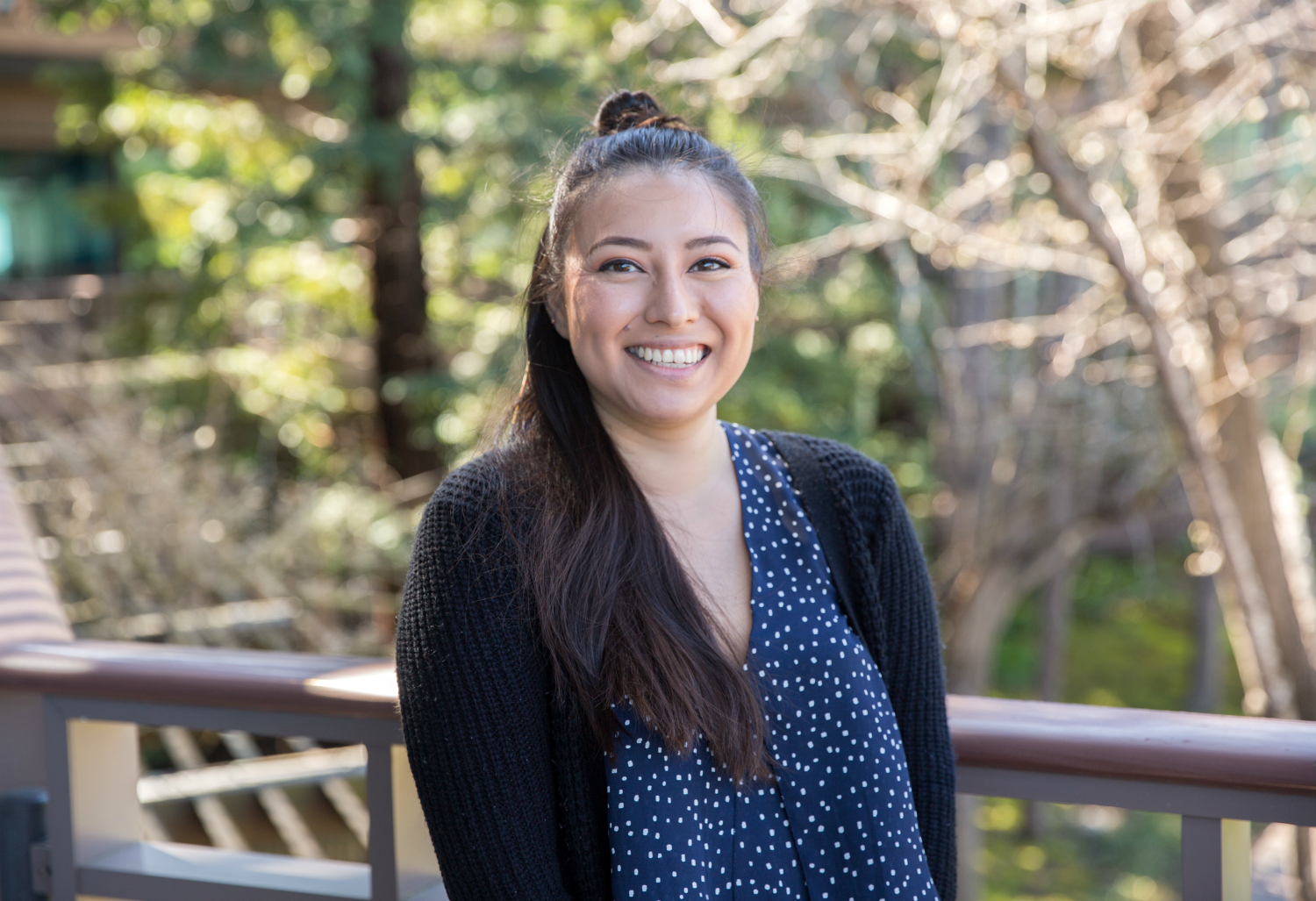 photo of diana leon garcia smiling in front of leafless trees and forest