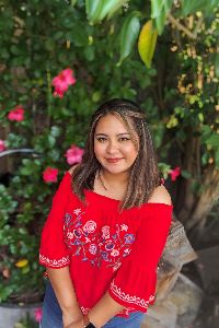 arley luna in red floral blouse sitting in front of green bush